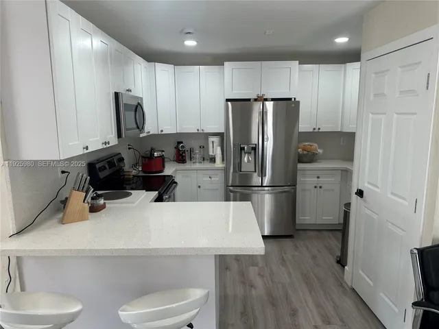 a kitchen with a refrigerator a stove and wooden floor