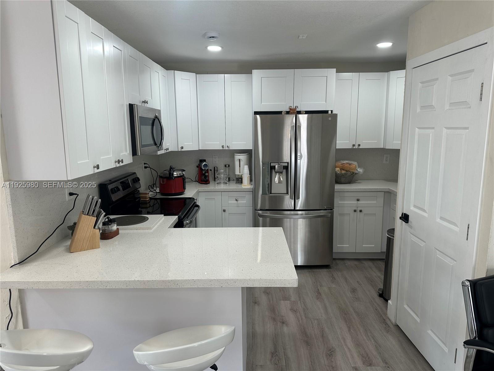 659 East 19th Street, Unit 659 Hialeah, FL 33013 - Photo 5 of 26 a kitchen with a refrigerator a stove and wooden floor
