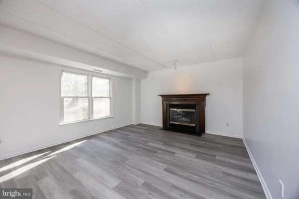 an empty room with wooden floor fireplace and windows