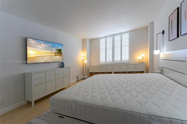 a bedroom with a bed and a flat tv screen on dresser