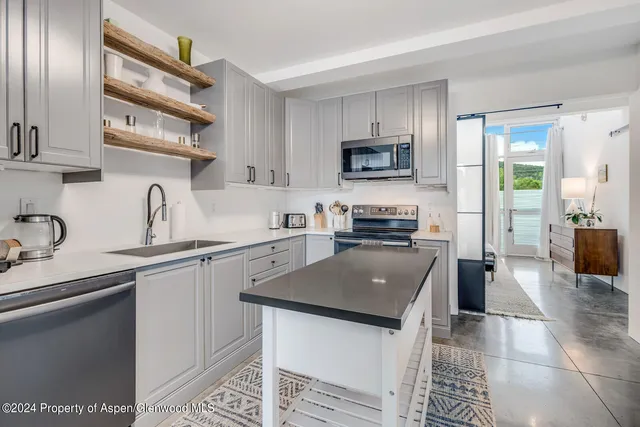 a kitchen with a sink a counter top space cabinets and stainless steel appliances