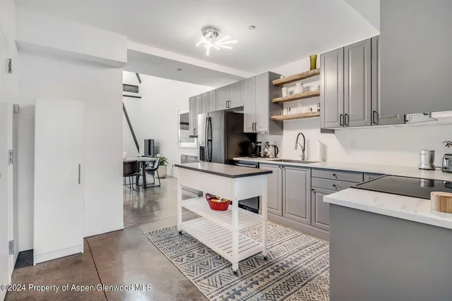 a kitchen with a sink dishwasher a stove a microwave oven and white cabinets with wooden floor