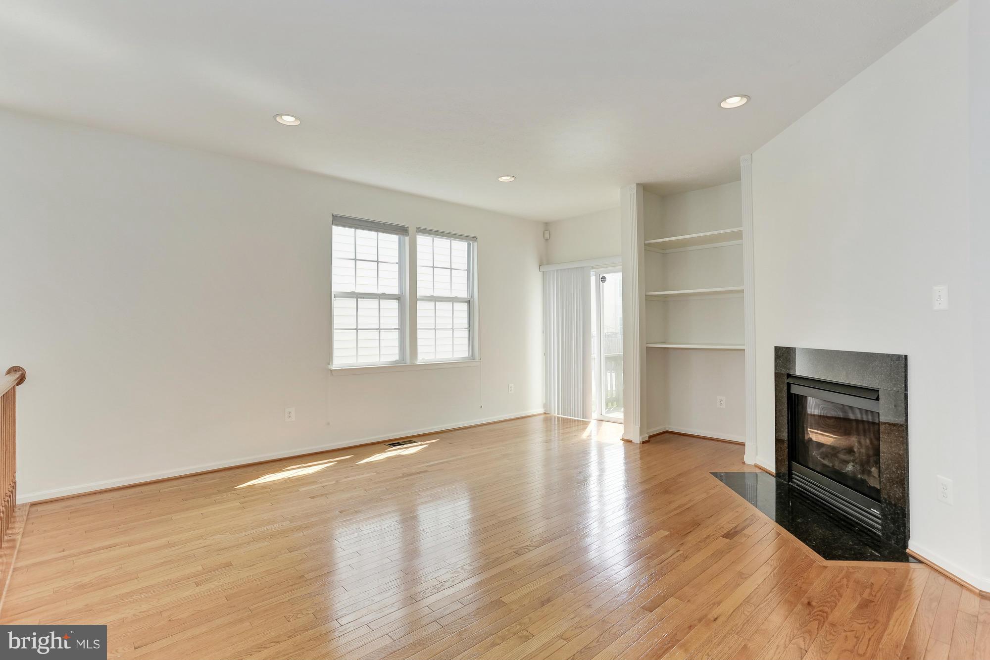 9637 Biggs Road Middle River, MD 21220 - Photo 11 of 30 an empty room with wooden floor fireplace and windows