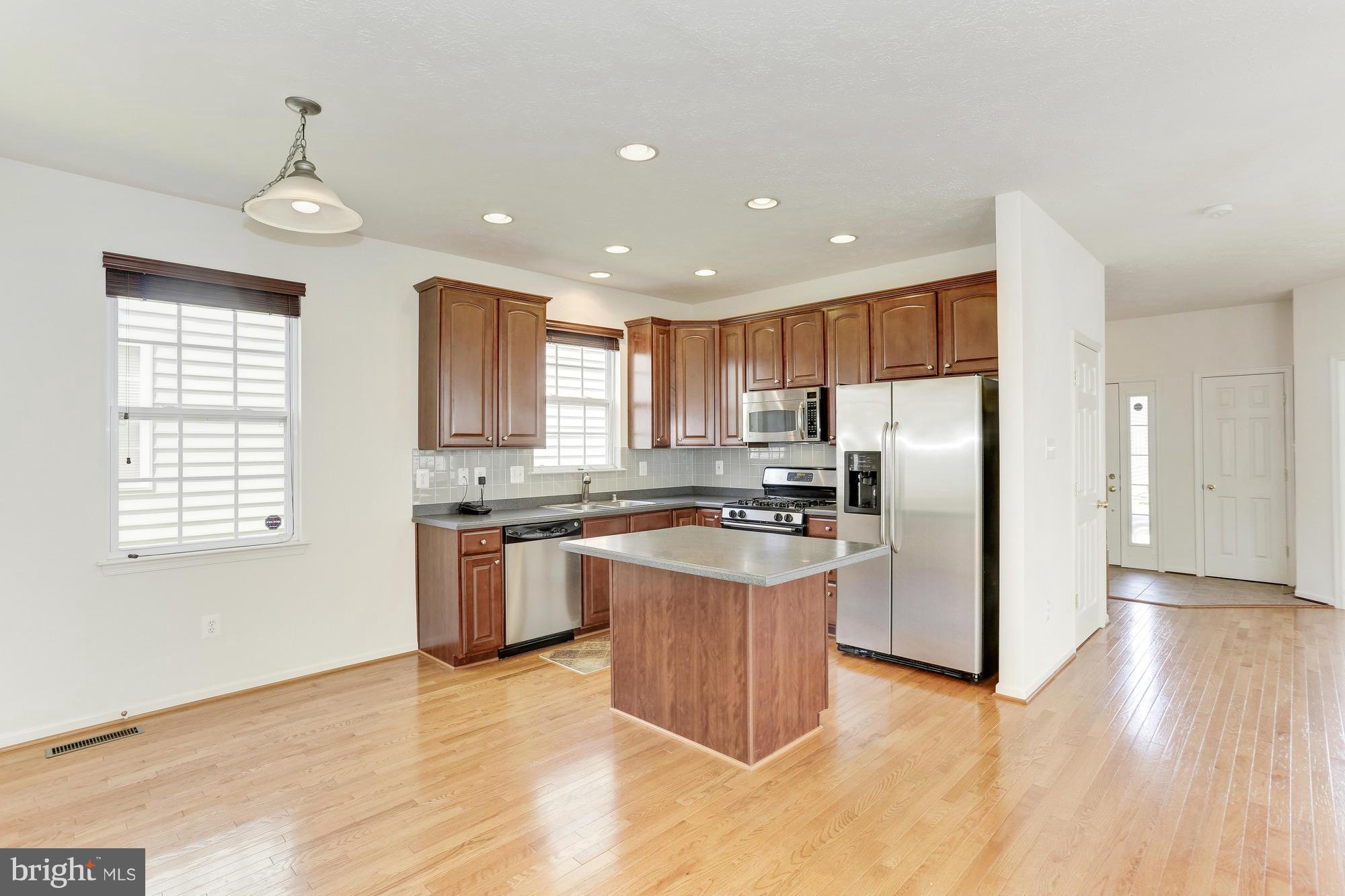 9637 Biggs Road Middle River, MD 21220 - Photo 12 of 30 a kitchen with stainless steel appliances granite countertop a refrigerator a sink dishwasher a stove and white countertops with wooden floor