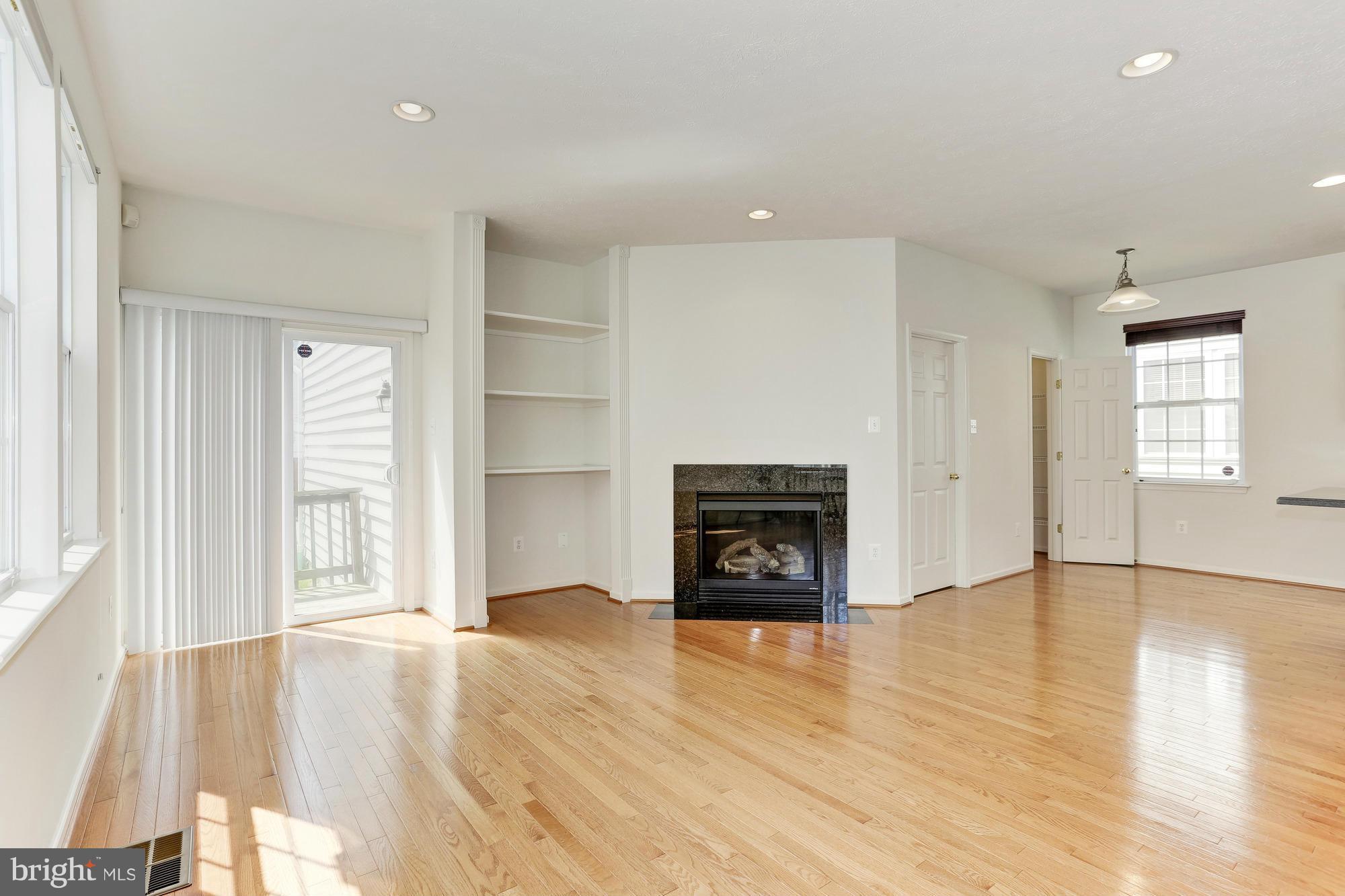 9637 Biggs Road Middle River, MD 21220 - Photo 8 of 30 an empty room with wooden floor a fireplace and windows