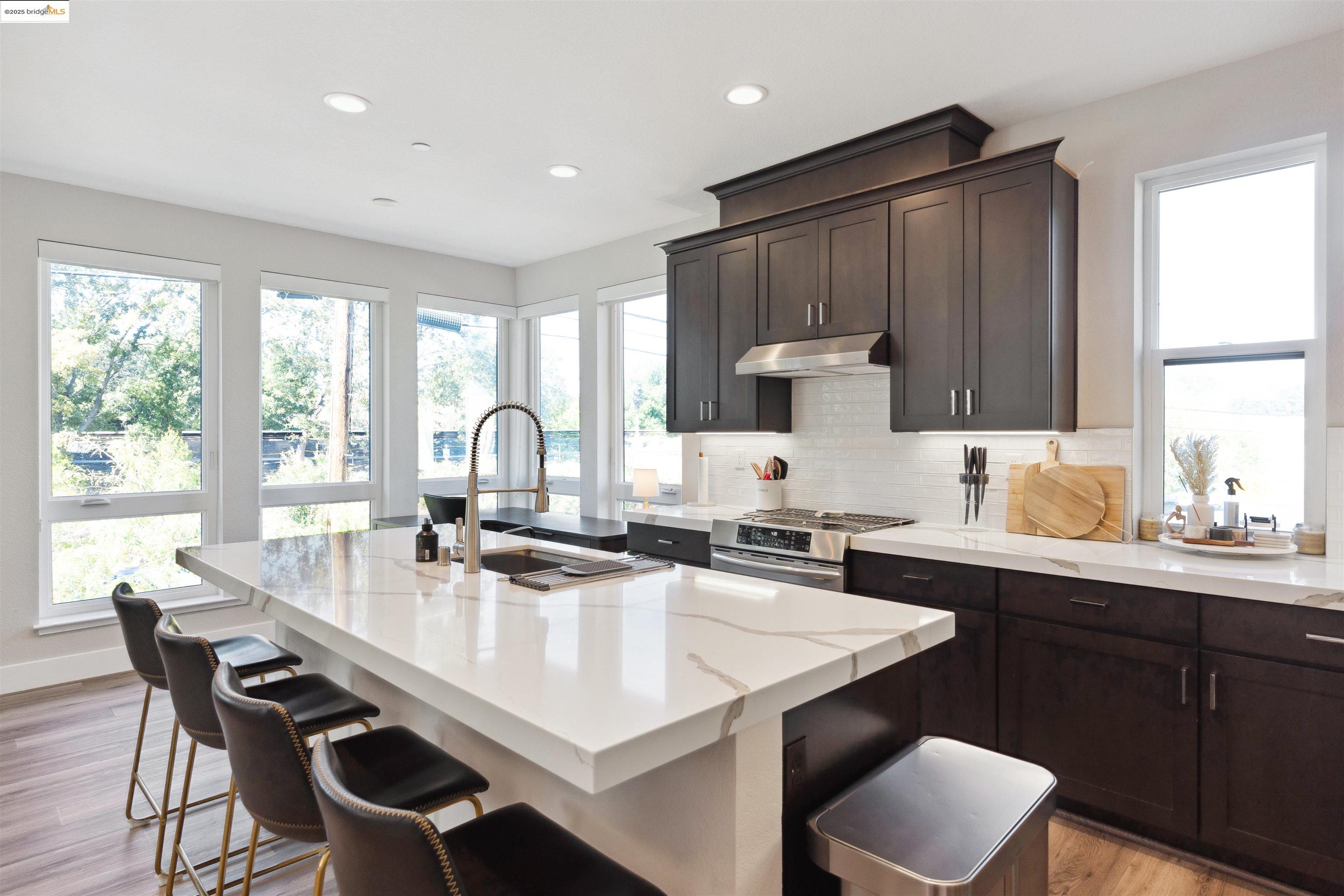 2640 Jones Road, Unit A Walnut Creek, CA 94597 - Photo 15 of 43 Kitchen featuring a center island with sink, light wood-type flooring, decorative backsplash, dark brown cabinets, and a breakfast bar