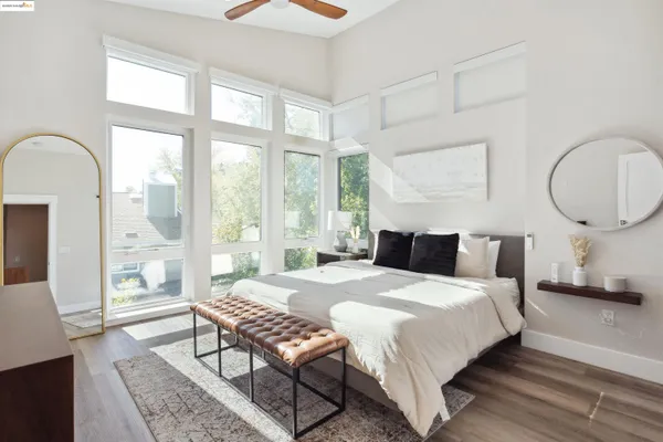 a bedroom with a bed a mirror and a large window with outer view