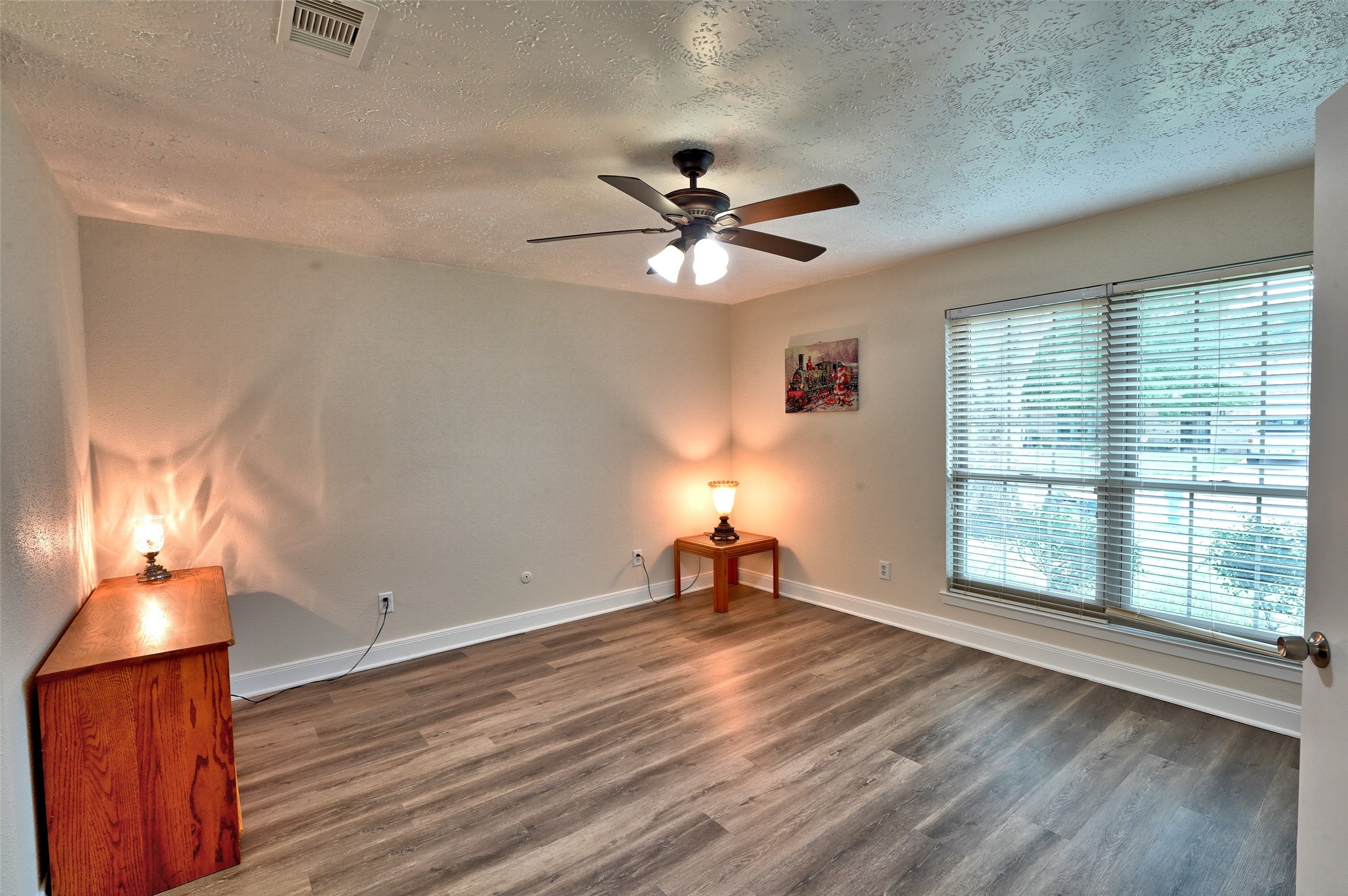 16715 Maplemont Drive Houston, TX 77095 - Photo 11 of 24 This Primary Bedroom features laminate wood-style flooring, neutral walls, and a ceiling fan. Large windows provide ample natural light, while subtle lighting fixtures add warmth.