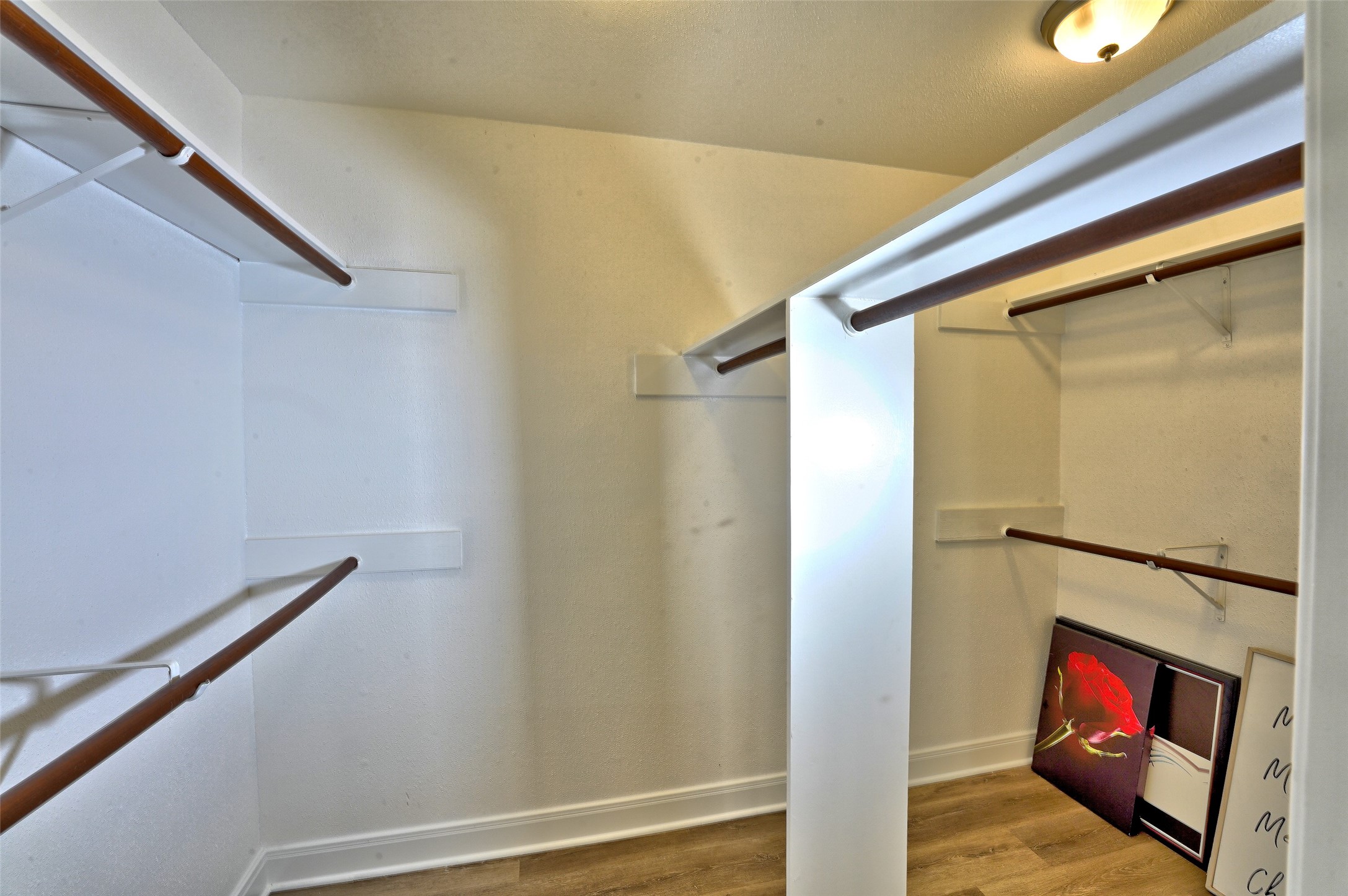 16715 Maplemont Drive Houston, TX 77095 - Photo 12 of 24 This photo showcases a spacious walk-in closet with multiple wooden hanging rods and shelves, ideal for ample storage. The neutral walls and ceiling light provide a bright and inviting space.