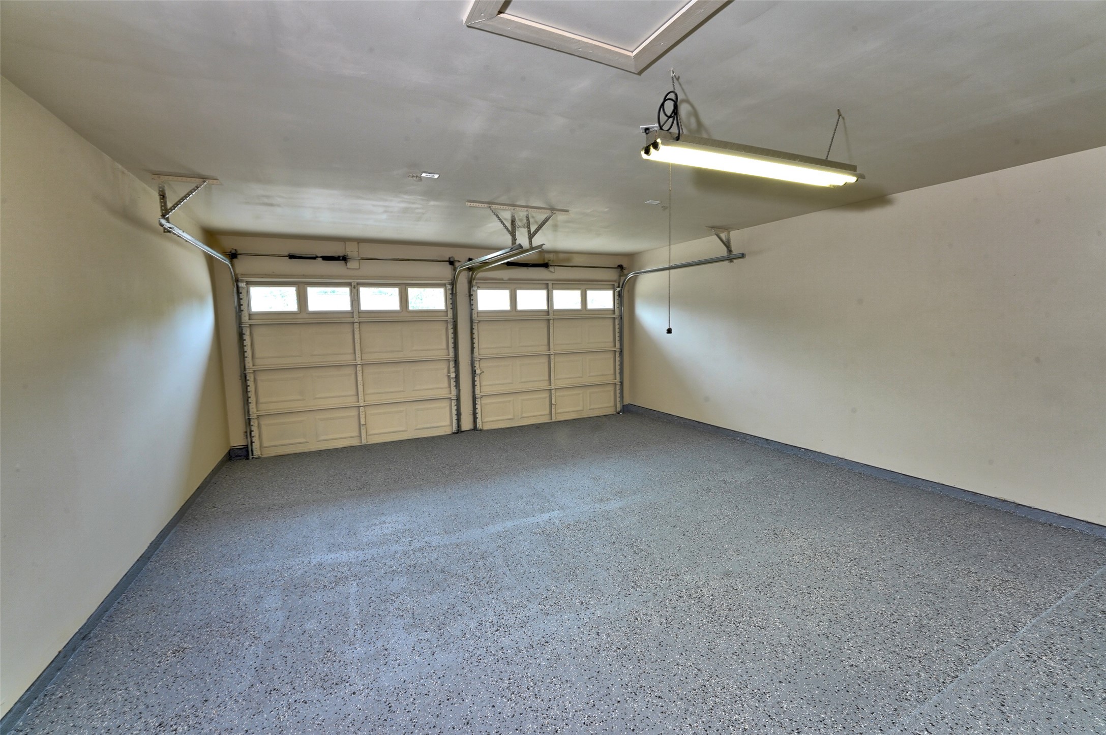 16715 Maplemont Drive Houston, TX 77095 - Photo 18 of 24 Clean garage with a double door and ample overhead lighting. The floor is finished with an Epoxy, speckled coating, providing a durable and attractive surface. Perfect for parking or storage.