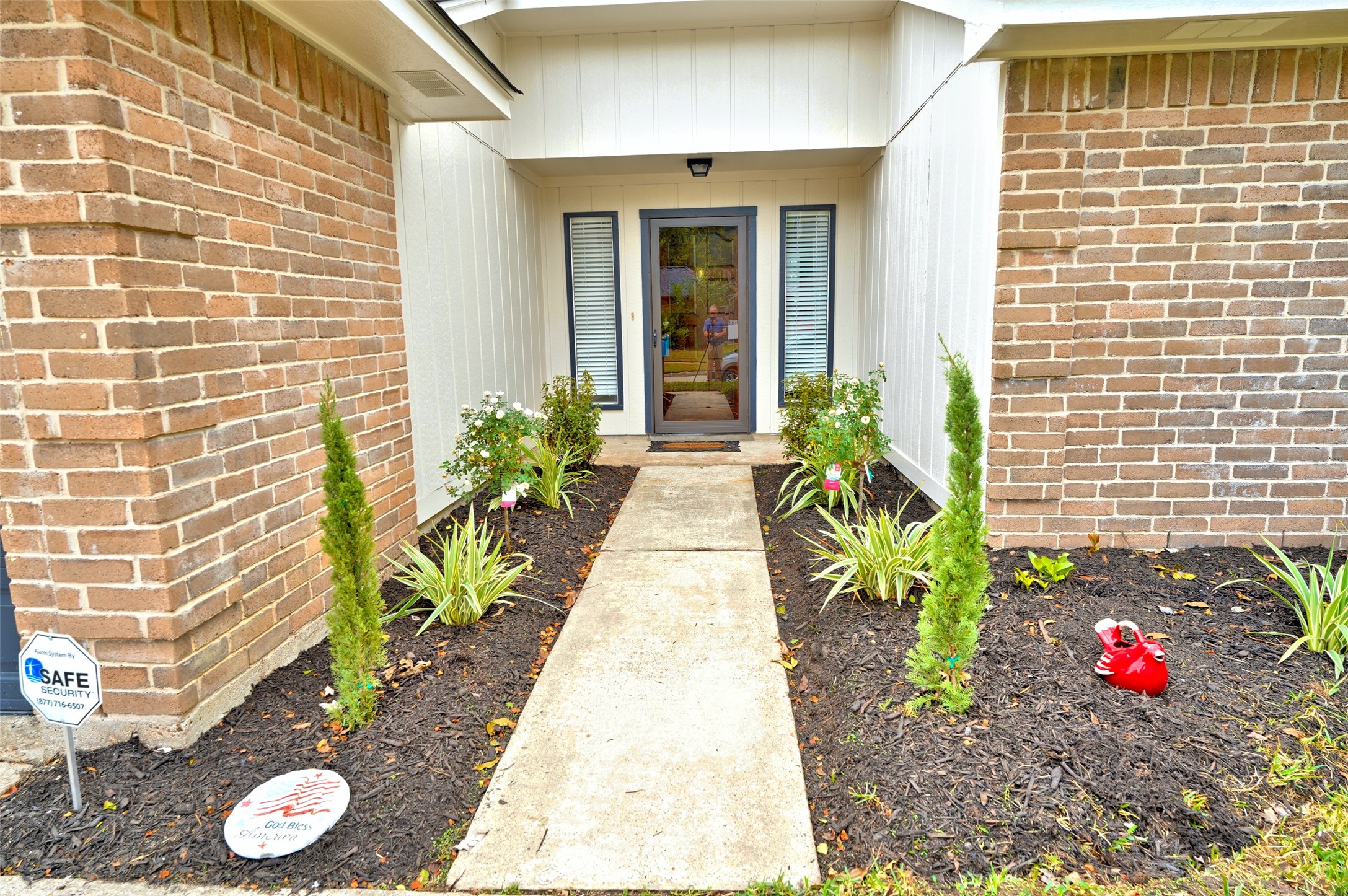16715 Maplemont Drive Houston, TX 77095 - Photo 2 of 24 A welcoming front entrance with a pathway leading to the front door. It's framed by neat flowerbeds featuring green plants and small shrubs, set against a combination of brick and white siding.