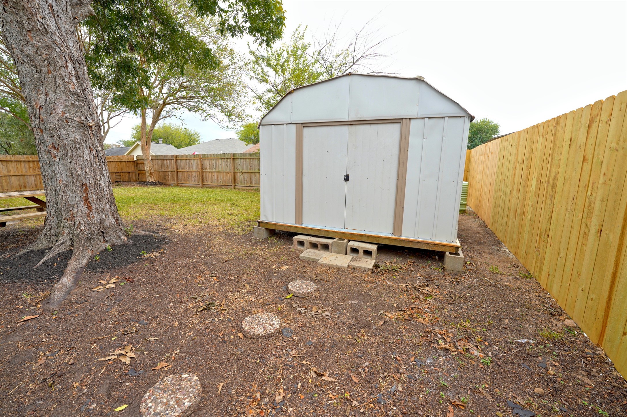 16715 Maplemont Drive Houston, TX 77095 - Photo 22 of 24 A spacious backyard features a large storage shed, surrounded by a wooden fence for privacy. The area includes mature trees and a grassy lawn, ideal for outdoor activities.