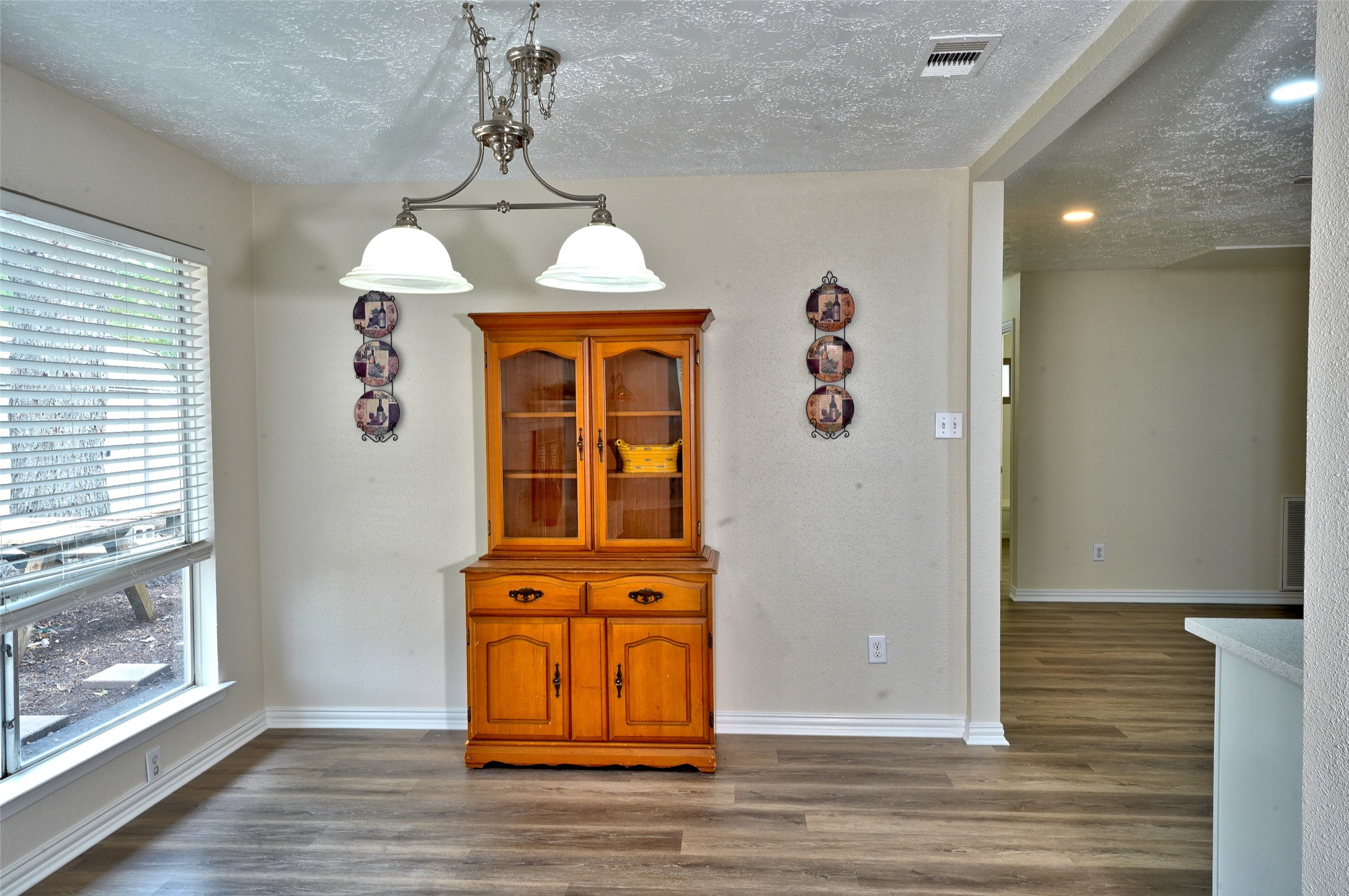 16715 Maplemont Drive Houston, TX 77095 - Photo 6 of 24 Bright dining area with large window, elegant light fixture, and wood-look flooring. Features a classic wooden hutch and connects to other living spaces.