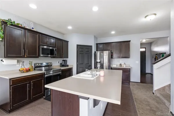 a kitchen with stainless steel appliances kitchen island granite countertop a stove refrigerator sink microwave and cabinets