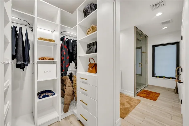 a view of walk in closet with clothes and shoes