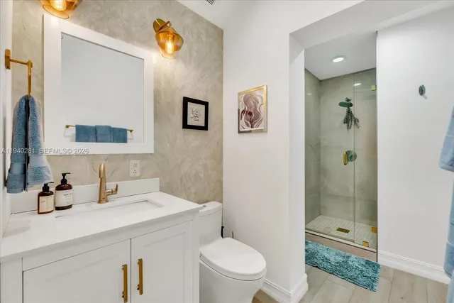 a bathroom with a toilet a sink a shower a mirror and vanity