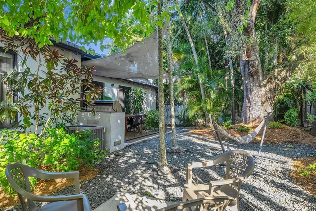 a backyard of a house with table and chairs under an umbrella