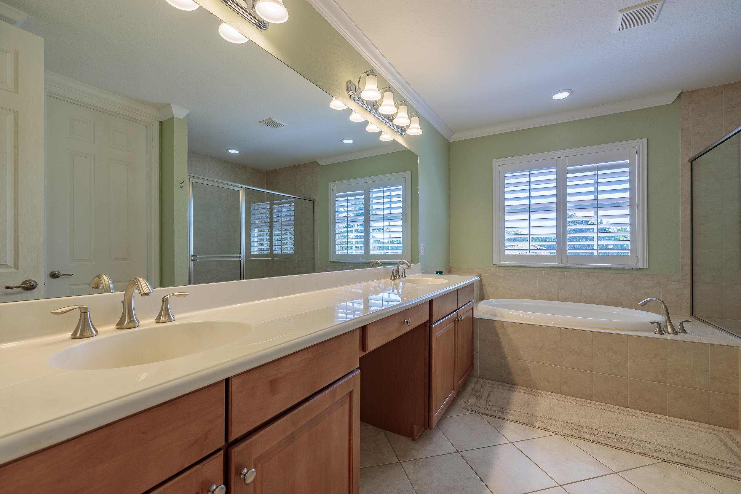 3285 Southwest Porpoise Circle Stuart, FL 34997 - Photo 24 of 69 a spacious bathroom with a granite countertop sink a large mirror and a bathtub with shower