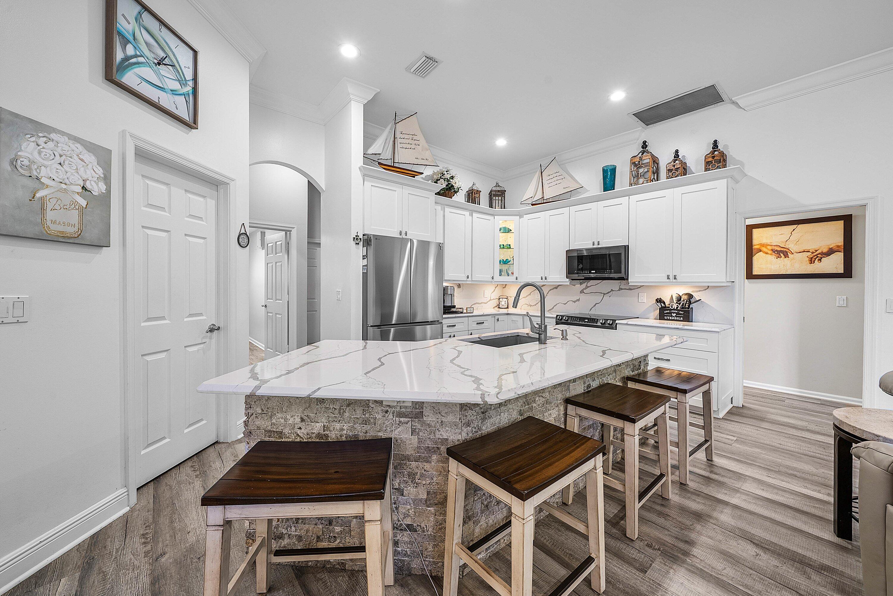 18670 Southeast Lakeside Way Jupiter, FL 33469 - Photo 14 of 56 a kitchen with stainless steel appliances kitchen island granite countertop a stove a refrigerator and white cabinets with wooden floors