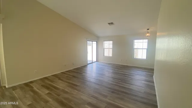 a view of an empty room with wooden floor and window