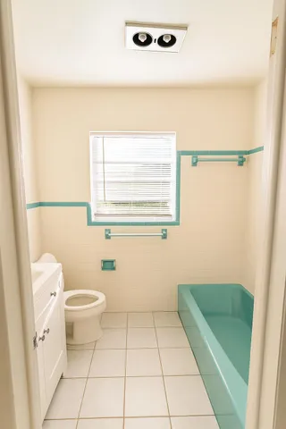 a bathroom with a sink a toilet a window and a shower