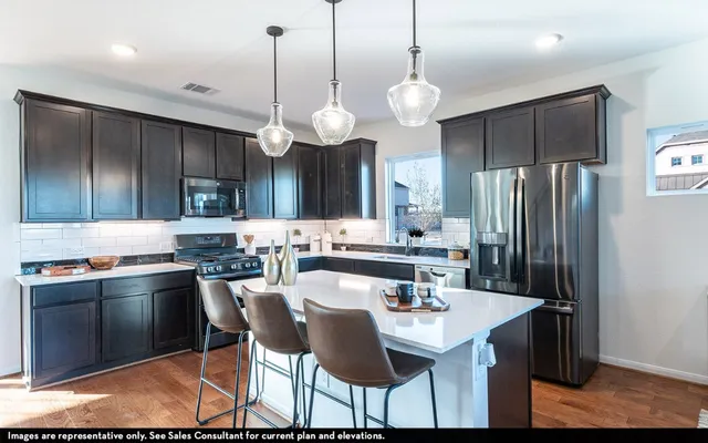 a kitchen with granite countertop a sink stainless steel appliances and chairs
