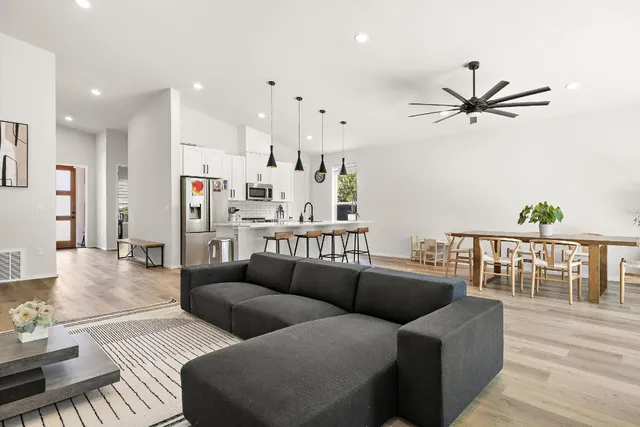 a living room with furniture kitchen view and a wooden floor