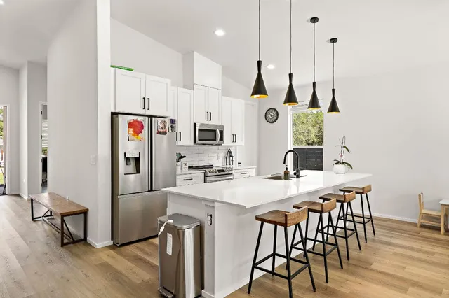 a kitchen with stainless steel appliances a dining table chairs and a refrigerator
