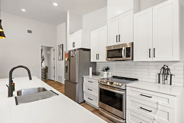 a kitchen with stainless steel appliances kitchen island a white stove top oven and white cabinets