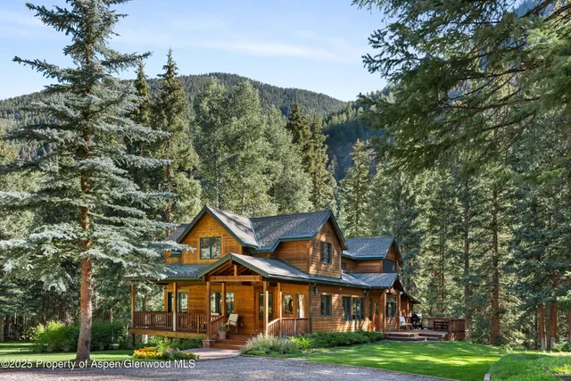 a view of a big house with a big yard and large trees