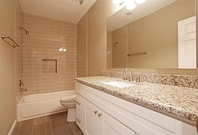 a bathroom with a granite countertop sink mirror vanity and toilet