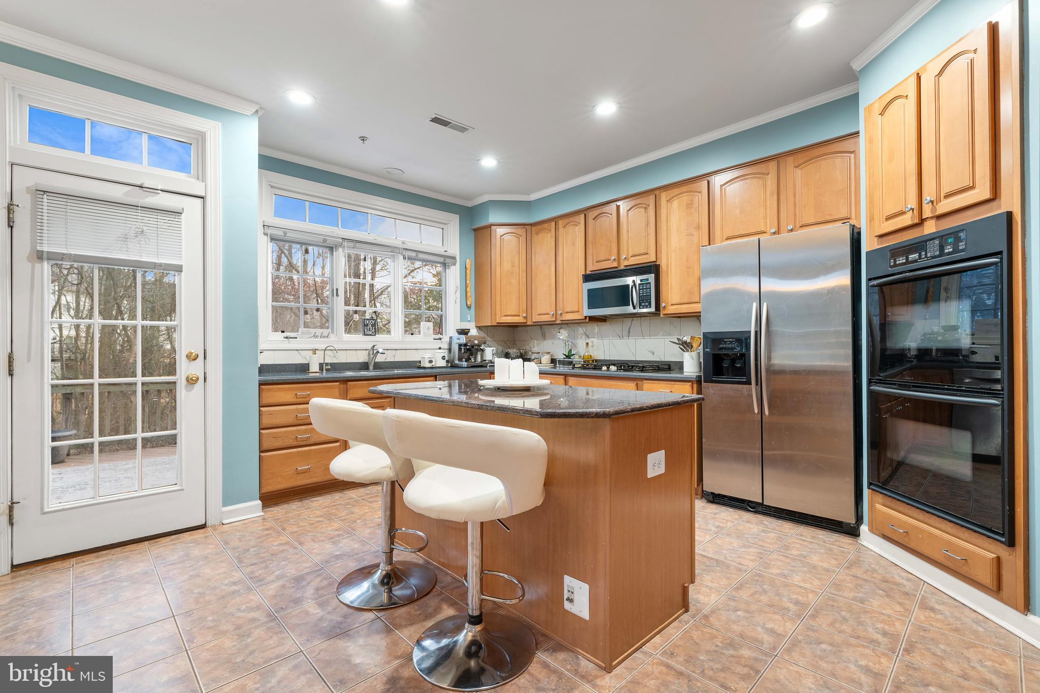 12461 Rose Path Circle Fairfax, VA 22033 - Photo 5 of 43 a kitchen with stainless steel appliances granite countertop a refrigerator a stove a sink a dining table and chairs with wooden floor