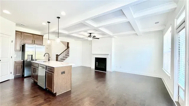 a kitchen with stainless steel appliances a refrigerator a sink a stove a kitchen island and chairs with wooden floor