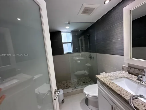a bathroom with a granite countertop toilet a sink and a mirror