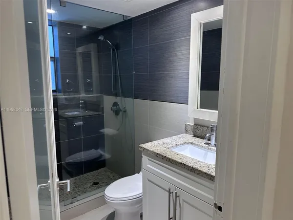 a bathroom with a granite countertop sink a toilet and shower