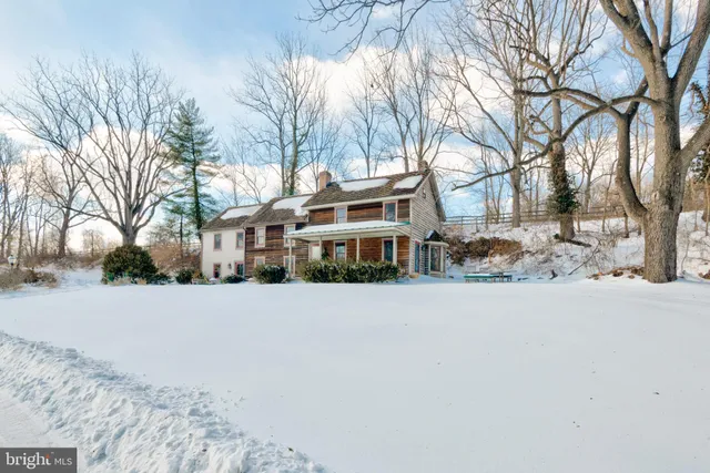 a front view of a house with a yard covered with snow and trees
