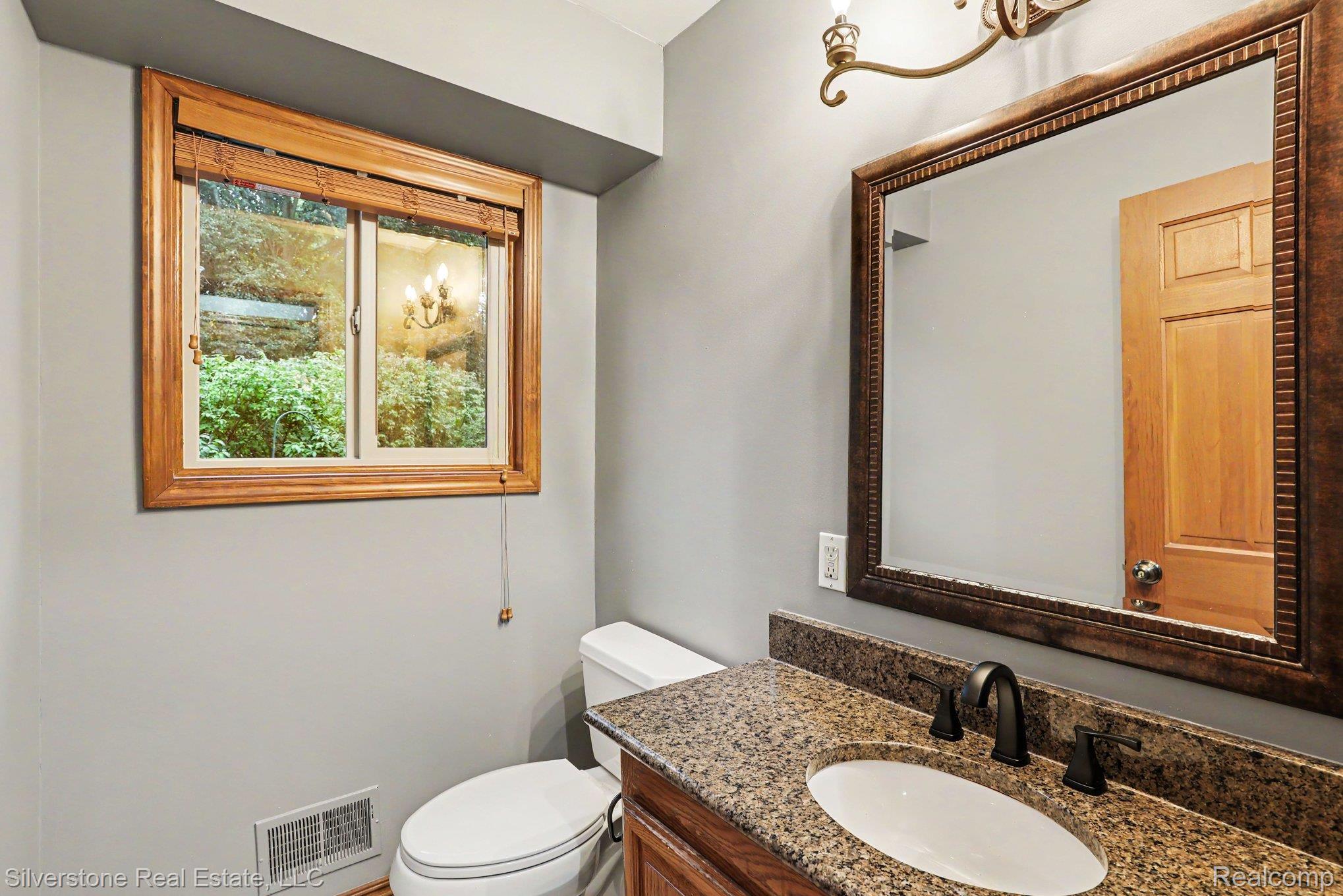 869 Timberline Drive Rochester, MI 48309 - Photo 10 of 29 Granite-style countertop with an undermount sink, dark bronze-finish faucet, and a large framed mirror