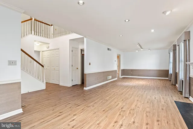 an empty room with wooden floor fireplace and windows