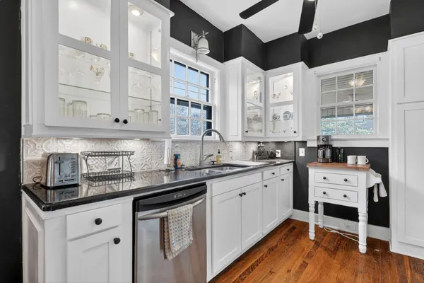a kitchen with stainless steel appliances granite countertop a stove a sink and white cabinets with wooden floor