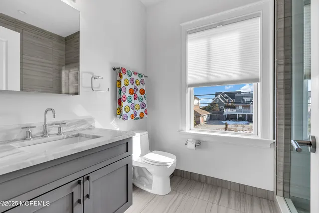 a bathroom with a granite countertop sink toilet and a window