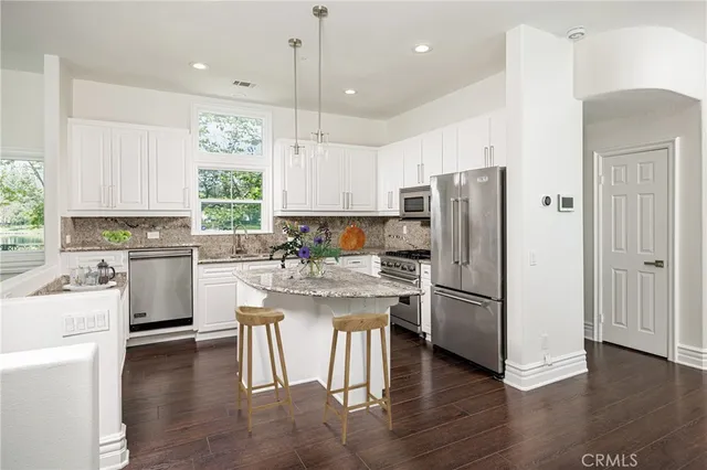 a kitchen with a refrigerator a sink dishwasher a stove and white cabinets with wooden floor