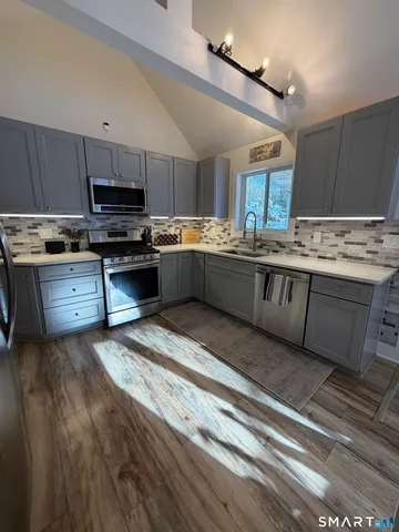 a large kitchen with kitchen island granite countertop a stove top oven a sink dishwasher a dining table and chairs with wooden floor