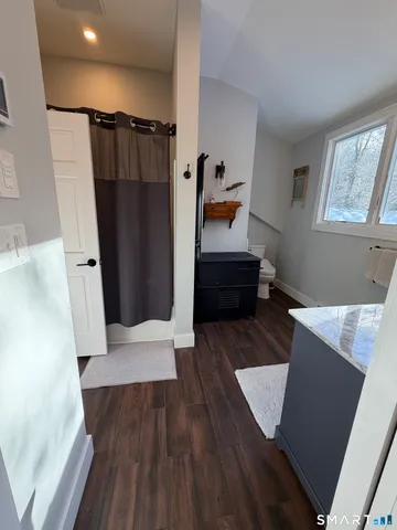 a walk in closet with wooden floor and window