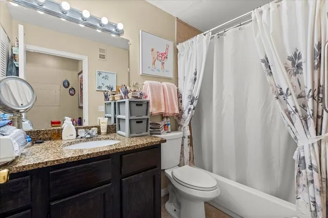 a bathroom with a granite countertop sink toilet and a mirror
