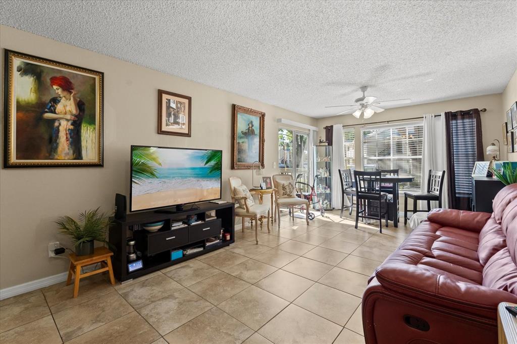1063 South Hiawassee Road, Unit 1615 Orlando, FL 32835 - Photo 3 of 20 a living room with furniture a dining table and a flat screen tv with wooden floor