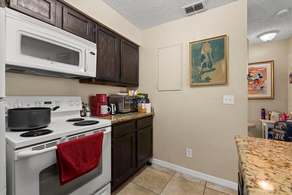 1063 South Hiawassee Road, Unit 1615 Orlando, FL 32835 - Photo 10 of 20 a kitchen with stainless steel appliances granite countertop a stove a microwave and cabinets