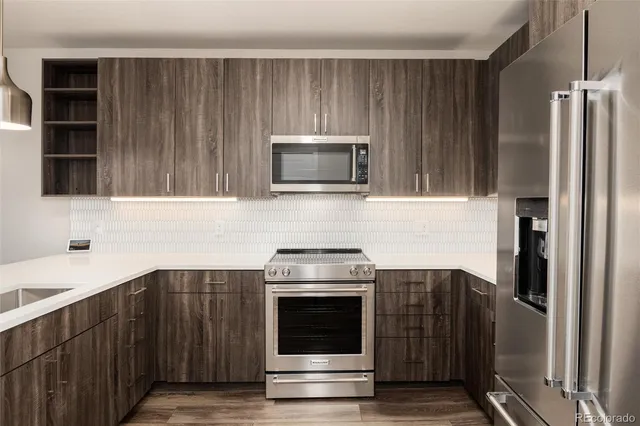 a kitchen with granite countertop a stove and a refrigerator with grey cabinets