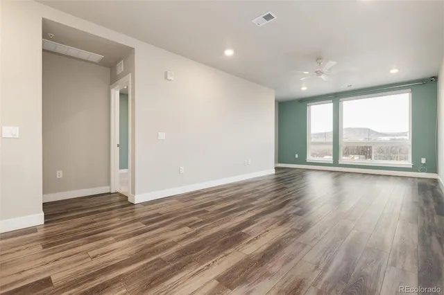 an empty room with wooden floor and windows