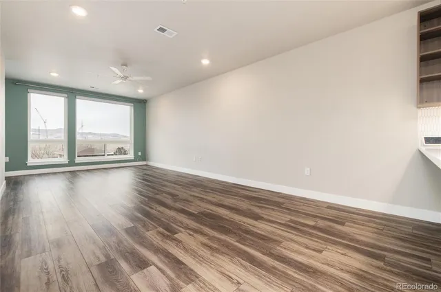 an empty room with wooden floor and windows