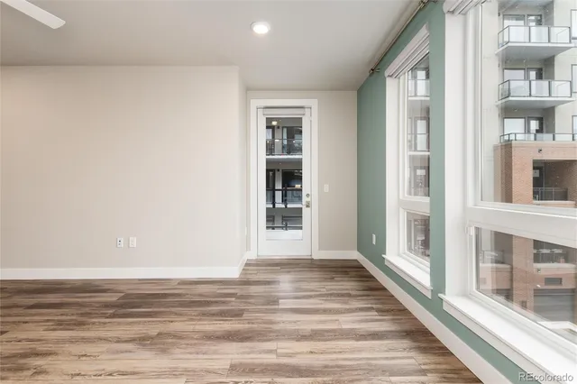 a view of an empty room with wooden floor and a window